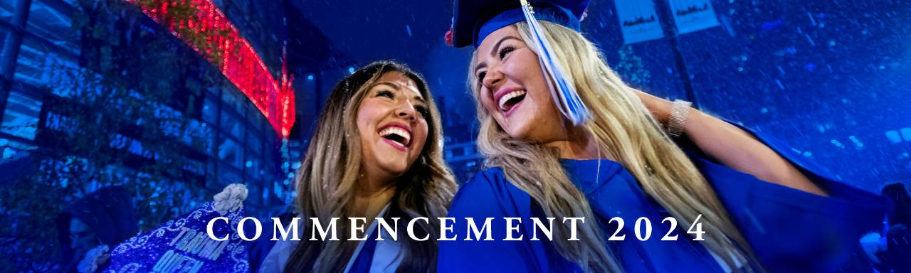 two graduates in blue cap and gowns smiling